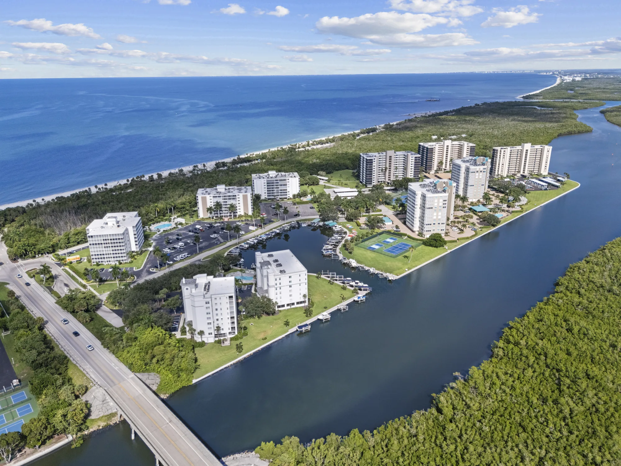 Aerial of the Bluebill peninsula at Vanderbilt Beach, with the Bluebill Avenue bridge, the Vanderbilt Channel, the peninsula’s four condominium communities and Delnor-Wiggins Pass State Park along the Gulf of Mexico, Naples, Florida