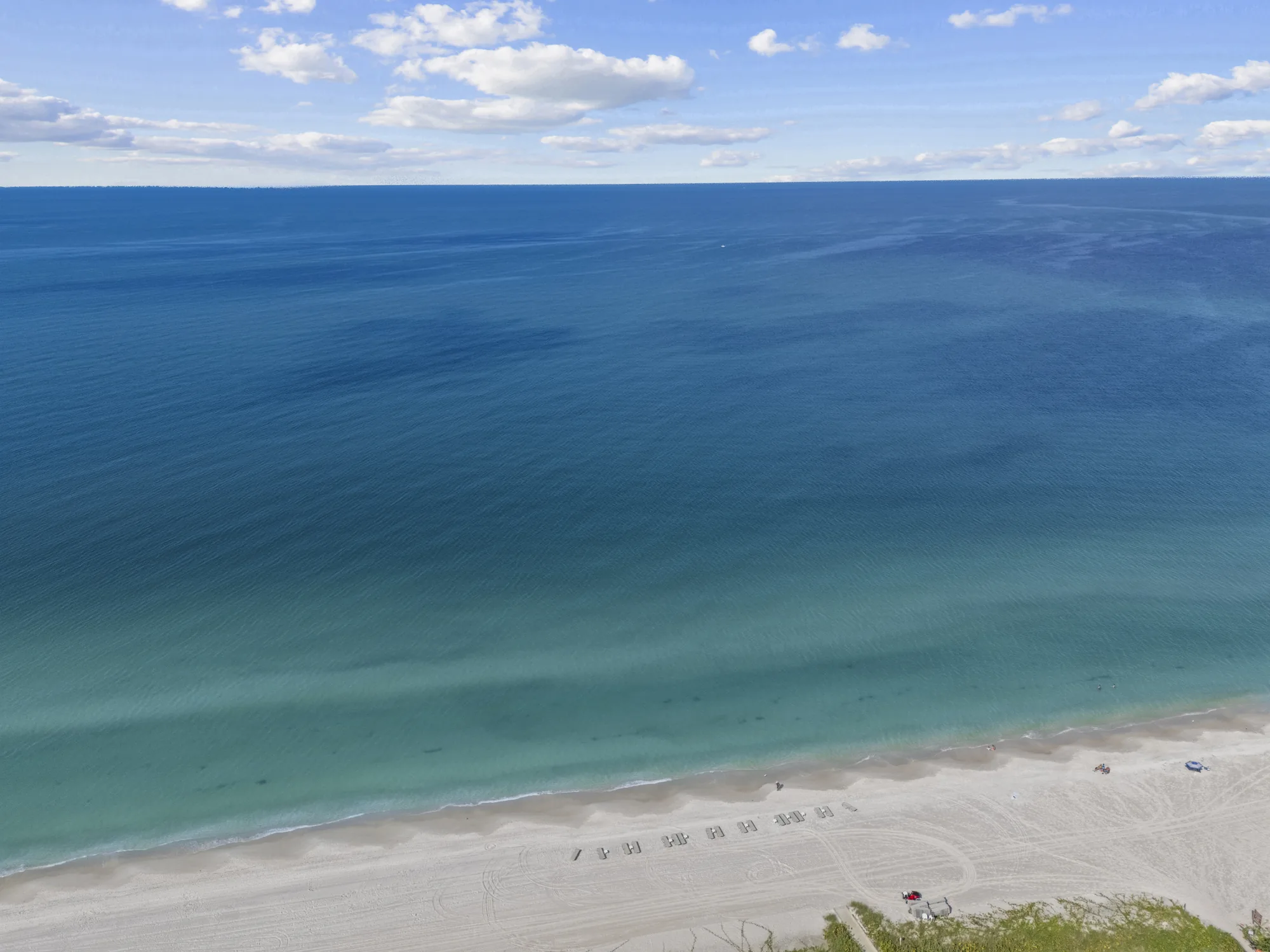 Aerial of the Gulf of Mexico and the beach in front of Moraya Bay, with beach chairs set out on the sand at the north end of Vanderbilt Beach, Naples, Florida