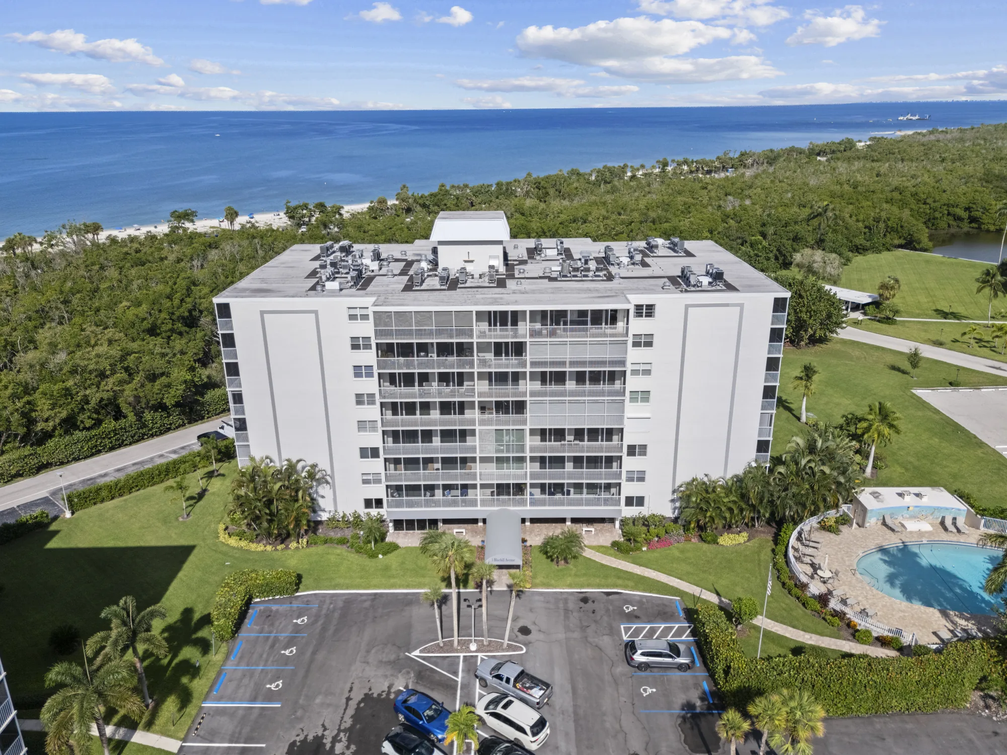 Aerial of the Vanderbilt Towers building at 5 Bluebill Avenue and its pool, with Delnor-Wiggins Pass State Park and the Gulf of Mexico beyond, Vanderbilt Beach, Naples, Florida